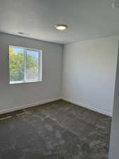 Unfurnished room with dark colored carpet and a textured ceiling