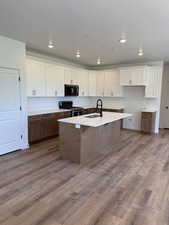 Kitchen with white cabinetry, dark wood-type flooring, appliances with stainless steel finishes, a breakfast bar, and a textured ceiling