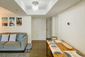 Living room with wood finished floors, wood walls, and a tray ceiling