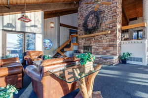 Carpeted living area featuring a wood ceiling with exposed beams, high vaulted ceiling, ceiling fan, plenty of natural light, and a fireplace