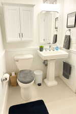 Half bathroom featuring toilet and a wainscoted wall