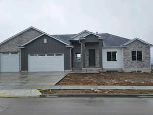 Craftsman-style home with an attached garage, driveway, stone siding, and board and batten siding