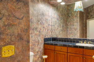 Half bathroom with vanity and wallpapered walls