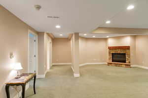 Below grade area with light colored carpet, recessed lighting, and a stone fireplace