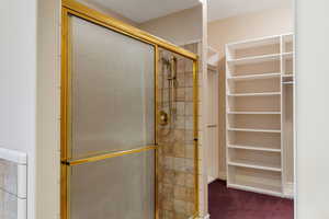 Bathroom with a stall shower and a walk in closet