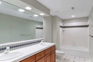 Full bathroom with bathing tub / shower combination, double vanity, recessed lighting, and light tile patterned floors