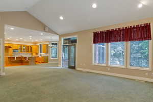 Unfurnished living room featuring recessed lighting, a chandelier, light colored carpet, and high vaulted ceiling