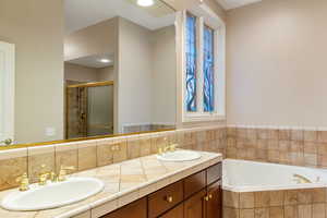 Full bath featuring a shower stall, double vanity, and a garden tub