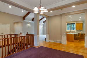 Empty room featuring beam ceiling, recessed lighting, light wood-style flooring, a chandelier, and ornamental molding