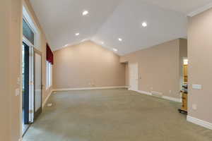 Empty room featuring vaulted ceiling, light carpet, and recessed lighting