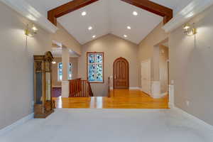 Foyer entrance with high vaulted ceiling, recessed lighting, light wood-type flooring, and light carpet