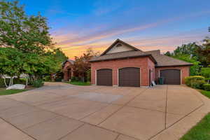 View of front of home featuring an attached garage, driveway, brick siding, and a shingled roof