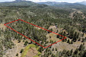 Aerial view of property and surrounding area with a mountainous background and property boundaries highlighted