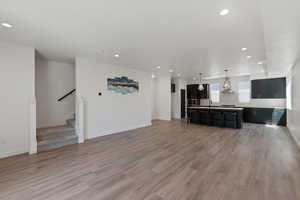 Unfurnished living room with recessed lighting, light wood-style flooring, and stairs
