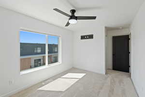 Carpeted empty room with baseboards and a ceiling fan