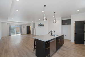 Kitchen featuring open floor plan, a kitchen bar, decorative light fixtures, stainless steel dishwasher, and recessed lighting