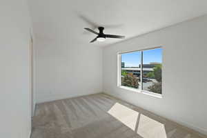 Empty room with light colored carpet and a ceiling fan