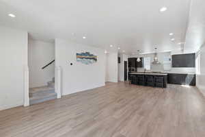 Unfurnished living room featuring recessed lighting, light wood-style flooring, and stairway