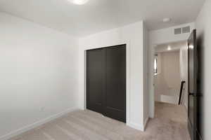 Unfurnished bedroom featuring a closet and light colored carpet