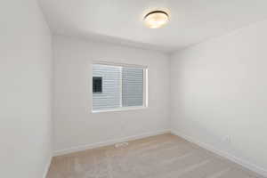 Unfurnished room featuring light carpet and baseboards