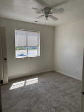 Carpeted empty room with a textured ceiling and ceiling fan