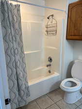 Full bath with shower / tub combo with curtain and light tile patterned floors