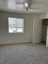 Unfurnished bedroom with a textured ceiling, light carpet, ceiling fan, and a closet