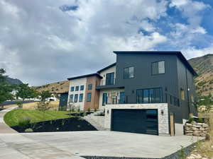 Modern home featuring a balcony, a mountain view, stone siding, and an attached garage