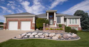 View of front of property with brick siding, concrete driveway, a front lawn, roof with shingles, and an attached garage