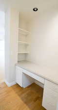 Unfurnished office with built in desk and light wood-style floors