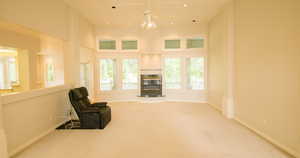 Living area with carpet floors, with fireplace, ceiling fan, a high ceiling, and recessed lighting