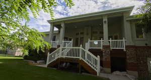 Rear view of house featuring a nice deck with double stairs leading down to lawn.