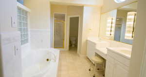 Primary bathroom featuring a jetted tub, vanity, light tile patterned floors, and a stall shower