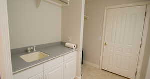 Laundry room with a sink and baseboards. Entrance to garage.