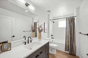 Full bathroom with shower / tub combo, vanity, and light wood-style floors