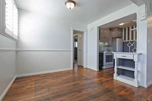 Kitchen with dark wood-style flooring, appliances with stainless steel finishes, open shelves, and light countertops
