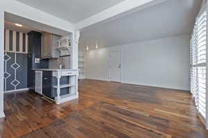 Kitchen featuring open shelves, dark wood-type flooring, open floor plan, and stainless steel dishwasher