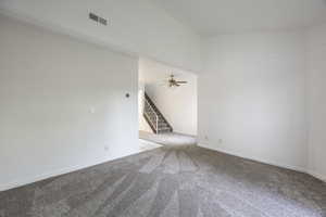 Carpeted empty room with stairs and ceiling fan