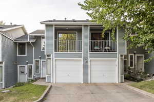 View of front of house with a balcony, an attached garage, concrete driveway, and roof with shingles