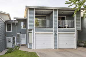 View of front of home featuring an attached garage, driveway, and a balcony