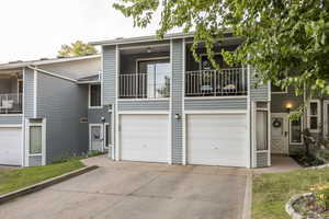View of front of home with a balcony, concrete driveway, and a garage