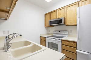 Kitchen featuring white appliances, light countertops, and light brown cabinets