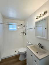 Bathroom with vanity, a textured ceiling, dark wood-type flooring, and a shower stall