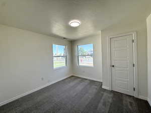 Unfurnished bedroom with dark colored carpet and a textured ceiling