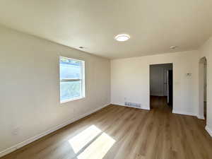 Spare room featuring light wood-style flooring, arched walkways, and a textured ceiling