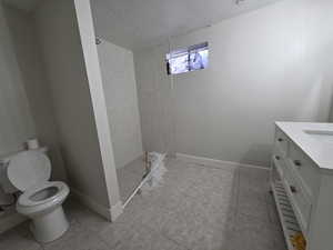 Bathroom featuring a stall shower, vanity, a textured ceiling, and light tile patterned floors