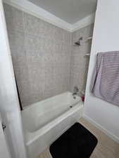 Bathroom featuring shower / tub combination, a textured ceiling, and light wood-type flooring