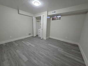 Finished basement with a textured ceiling and wood finished floors