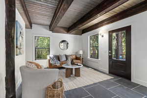 Living area with beamed ceiling and tile patterned flooring