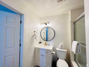 Full bathroom featuring a textured ceiling, a shower stall, and vanity
